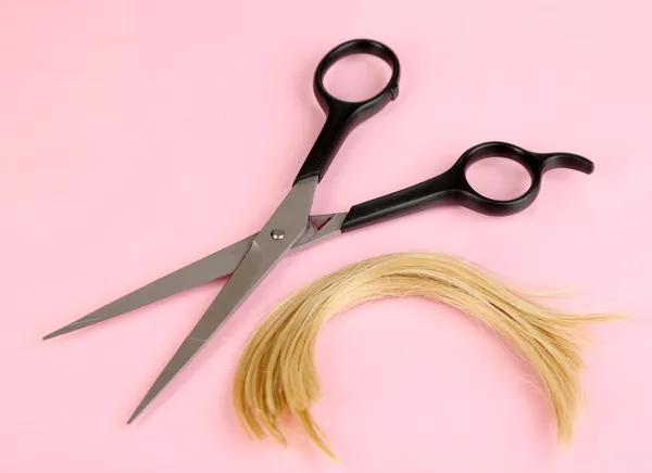 Pieces of hair cut with scissors on pink background — Stock Photo, Image