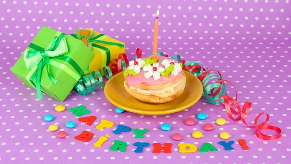 Colorful birthday cake with candle and gifts on pink background — Stock Photo, Image