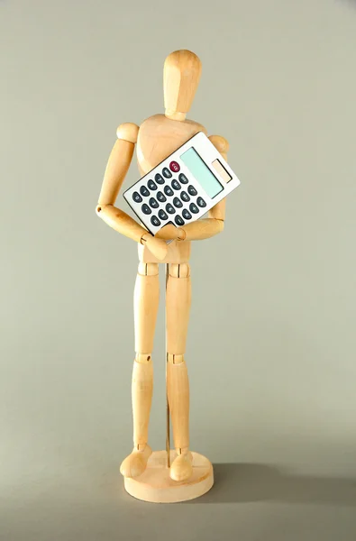 Wooden mannequin with calculator on grey background — Stock Photo, Image