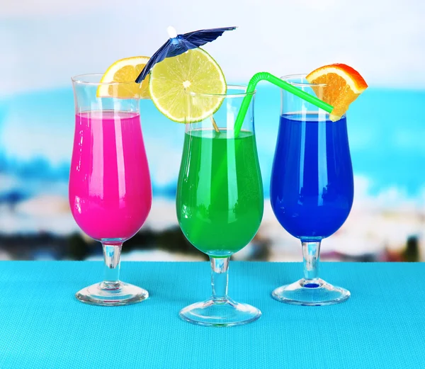 Glasses of cocktails on table near pool — Stock Photo, Image