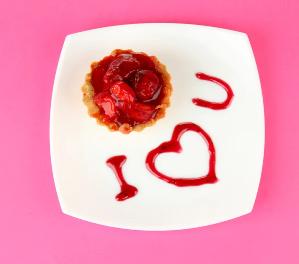 Zoete cake met aardbei en saus op plaat, op een achtergrond met kleur — Stockfoto