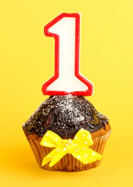 Birthday cupcake with chocolate frosting on yellow background — Stock Photo, Image