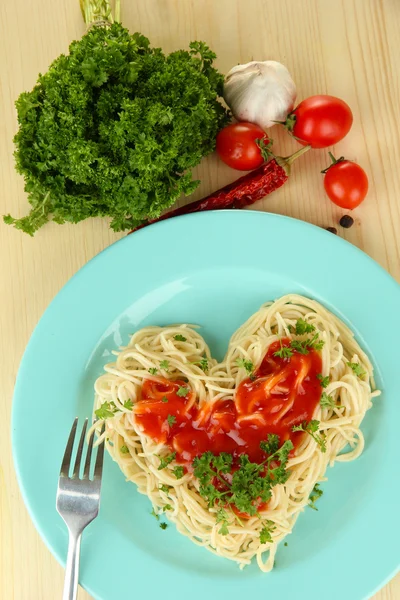 Spaghettis cuits soigneusement disposés en forme de coeur et garnis de sauce tomate, sur fond de bois — Photo