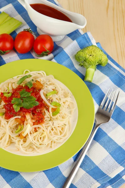 Leckere Spaghetti mit Sauce und Gemüse auf Teller auf Holztisch in Großaufnahme — Stockfoto