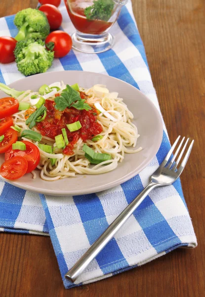 Spaghetti saporiti con salsa e verdure su piatto su tavolo di legno primo piano — Foto Stock