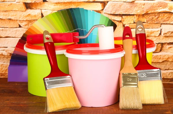 Set for painting: paint pots, brushes, paint-roller, palette of colors on stone wall background — Stock Photo, Image