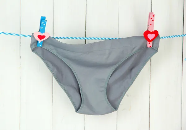 Womans panties hanging on a clothesline, on white wooden background — Stock Photo, Image