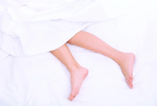 Belos pés de uma jovem deitada na cama de perto — Fotografia de Stock