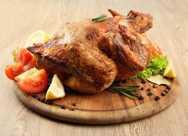 ahşap masa üzerinde plaka üzerinde sebze ile bütün kavrulmuş tavuk