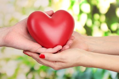 kadın ve adam ellerini, yeşil zemin üzerine kırmızı kalp