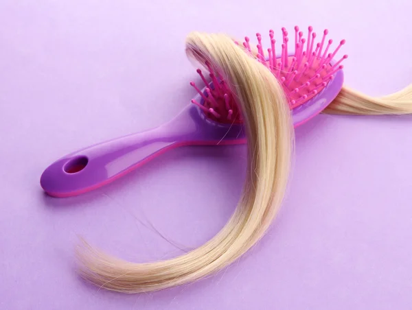 Escova de pente com cabelo, no fundo roxo — Fotografia de Stock