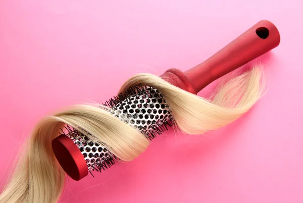 Peigne brosse avec cheveux, sur fond rose — Photo