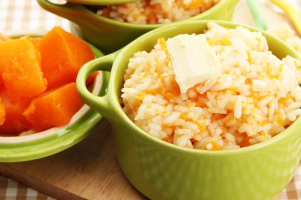 Taste rice porridge with pumpkin in saucepans on tablecloth backgroun — Stock Photo, Image