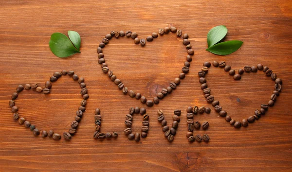 咖啡豆与木制背景上的叶子 — 图库照片