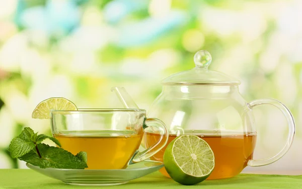 Xícara de chá com hortelã e limão na mesa em fundo brilhante — Fotografia de Stock
