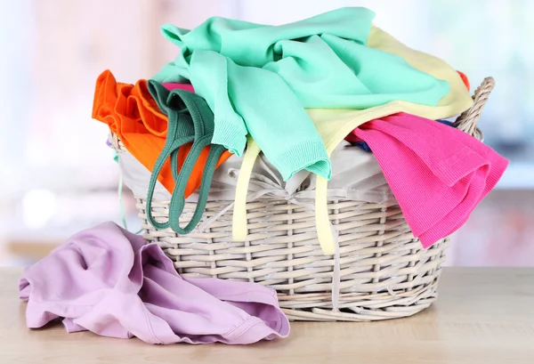 Clothes in wooden basket on table in room — Stock Photo, Image