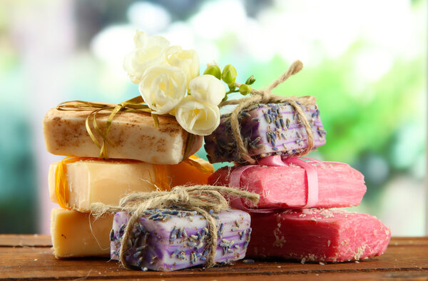 Естественное мыло ручной работы, на деревянном столе, на зеленом фоне
