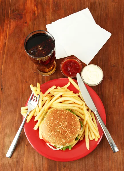 Tasty cheeseburger with fried potatoes and cold drink, on wooden background — Stock Photo, Image