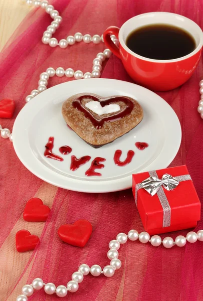 Galleta de chocolate en forma de corazón con taza de café en mantel rosa de cerca —  Fotos de Stock