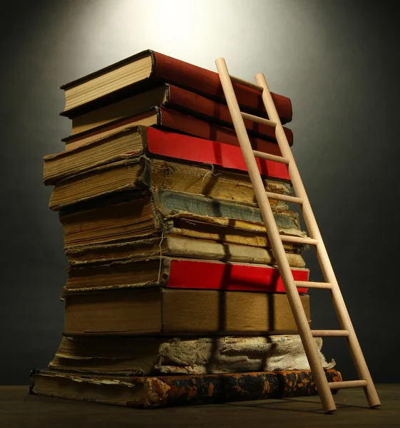 Stare książki i drabiny drewniane, na szarym tle — Zdjęcie stockowe