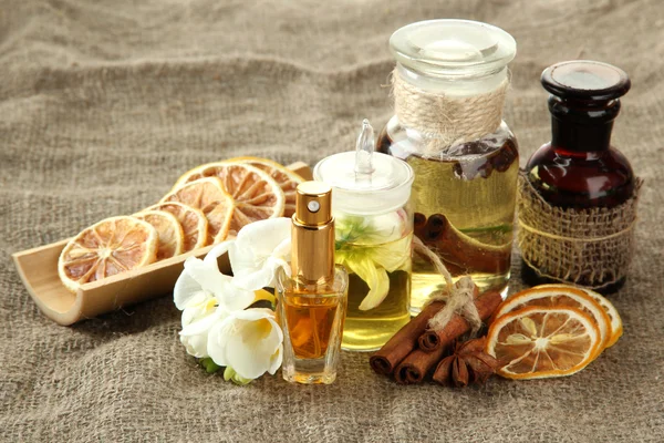 Bouteilles avec des ingrédients pour le parfum sur fond de toile de jute — Photo