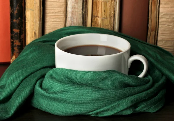 Kopje koffie verpakt in sjaal op boeken achtergrond — Stockfoto