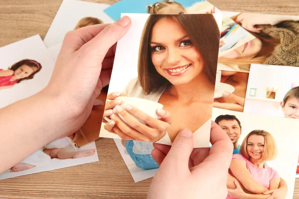 Photos in hands on wooden table — Stock Photo, Image