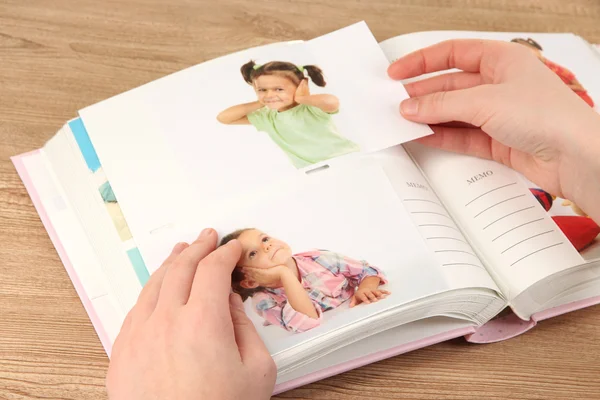 Fotos en manos y álbum de fotos en mesa de madera — Foto de Stock