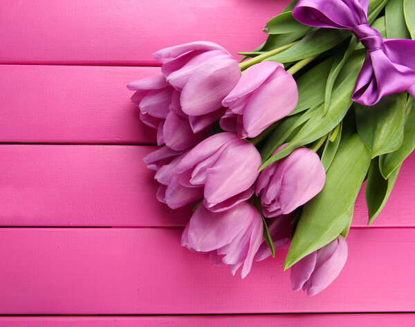 Beautiful bouquet of purple tulips on pink wooden background