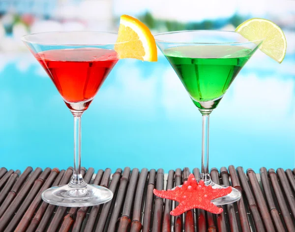 Glasses of cocktails on table near pool — Stock Photo, Image