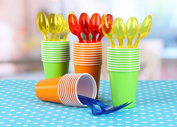 Cups, spoons and forks, of different colors on bright background — Stock Photo, Image