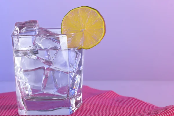 Ice in a glass on a color background — Stock Photo, Image