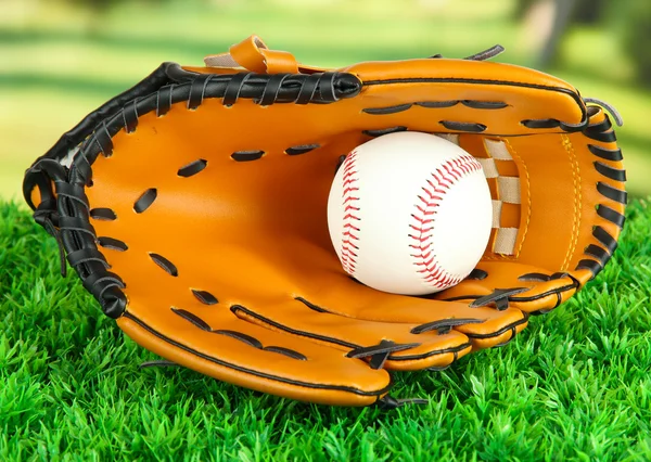 Honkbal handschoen en bal op gras in park — Stockfoto