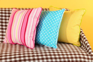 kanepede sarı arka plan üzerinde renkli yastıklar