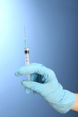 Doktor holding şırınga ile mavi arka plan üzerinde bir aşı