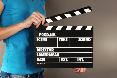 Film üretim clapper panosundaki gri arka plan üzerinde eller