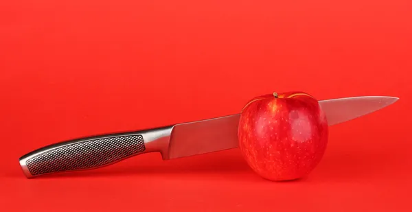 Pomme rouge et couteau sur fond rouge — Photo