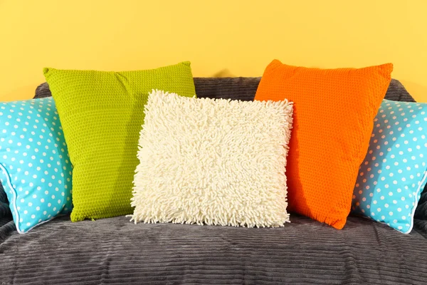 Almohadas de colores en el sofá sobre fondo amarillo —  Fotos de Stock