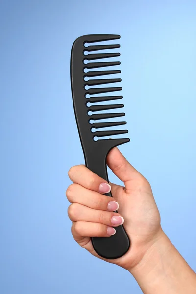 Black comb in female hand on color background — Stock Photo, Image