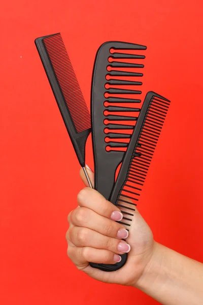 Three combs in female hand on color background — Stock Photo, Image