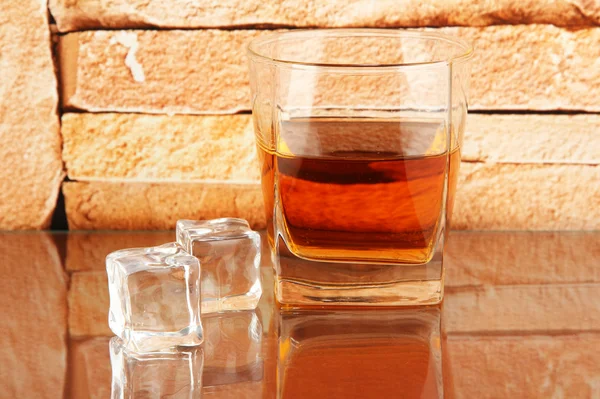 Verre de whisky et de glace sur fond de mur de briques — Photo