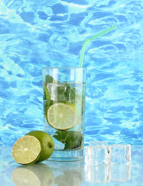 Glas Wasser mit Eis, Minze und Kalk auf Meeresgrund — Stockfoto