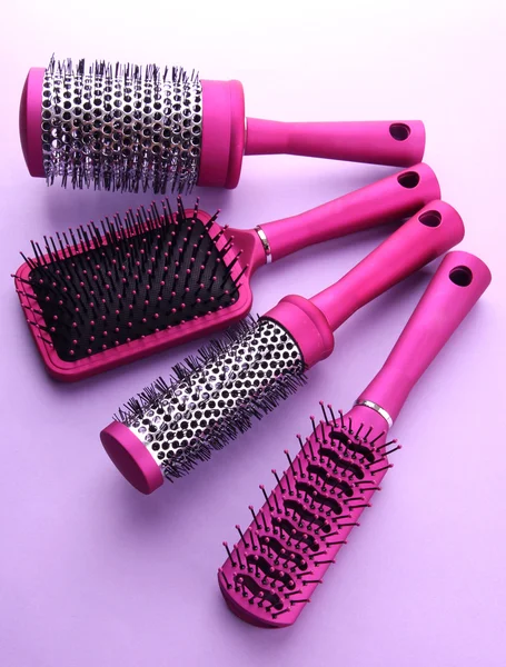 Comb brushes on purple background — Zdjęcie stockowe