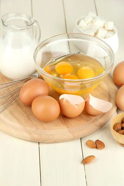 Uovo rotto in ciotola e vari ingredienti accanto a loro sul tavolo di legno primo piano — Foto Stock