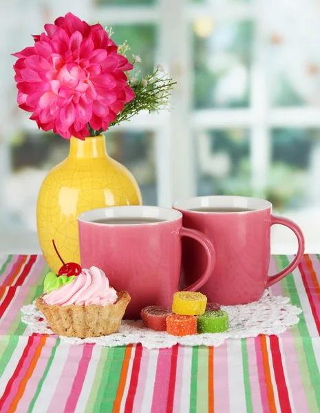 Tazas de té con pastel, dulces y flores en la mesa en la habitación — Foto de Stock