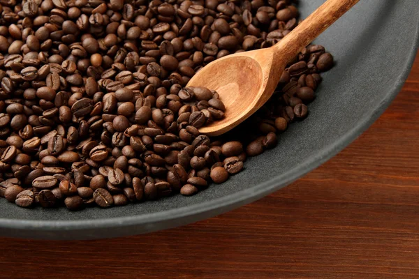 Black wok pan with coffee beans on wooden table, close up — Stock Photo, Image