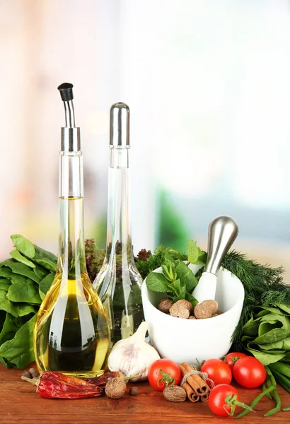 Composición de mortero, botellas con aceite de oliva y vinagre, y hierbas verdes, sobre fondo brillante —  Fotos de Stock