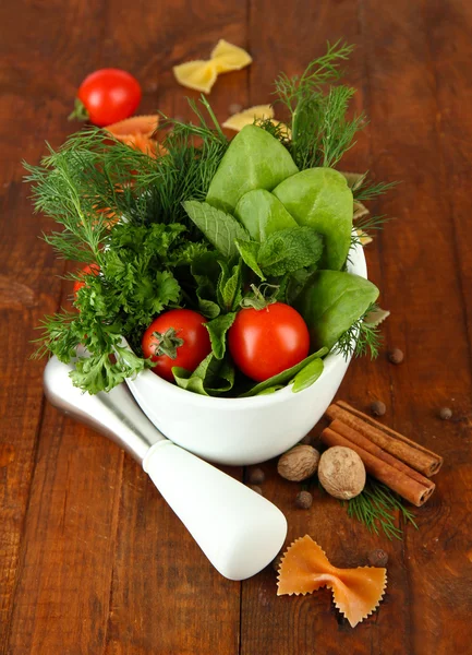 Kräuter und Gewürze im Keramikmörtel, auf Holzgrund — Stockfoto