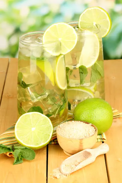 Glasses of cocktail with lime and mint on wooden table on bright background — Stock Photo, Image
