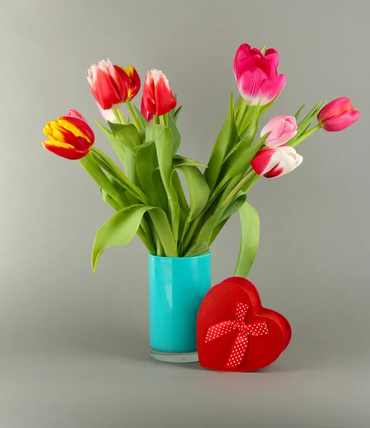 Beautiful tulips in bucket with gifts on grey background — Stock Photo, Image